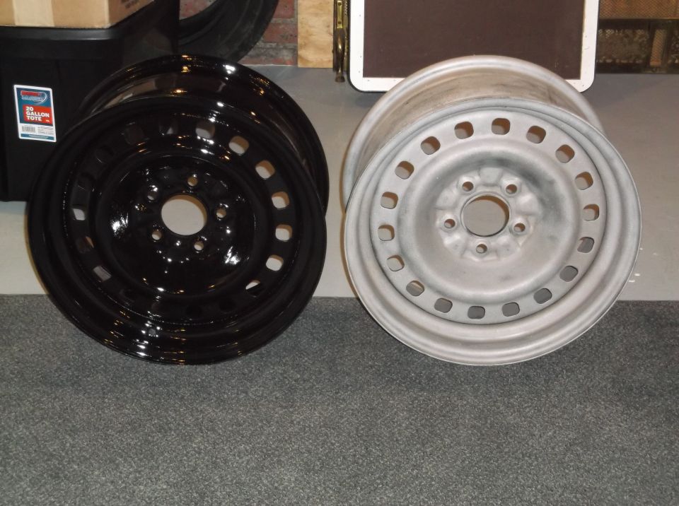 Two car wheels, one black and one silver, on a carpeted floor.