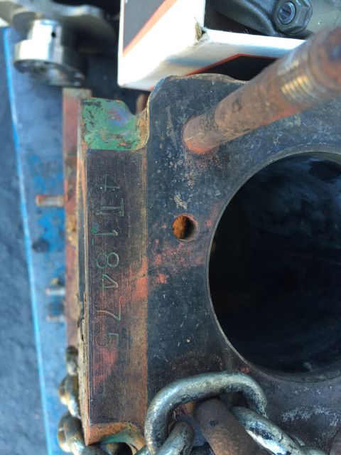 1946 Jeep Willys - A close-up view of a rusty engine block with the serial number "4118475" stamped vertically on its side. A metal chain is visible in the fo…