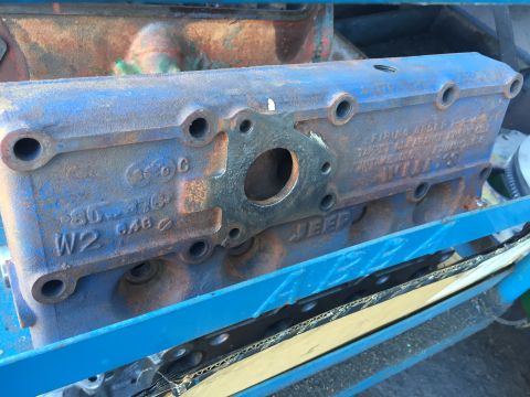 1946 Jeep Willys - A close-up, slightly angled view of a blue, cast iron engine cylinder head with visible rust. Text stamped on the head reads "JEEP" and "W2…