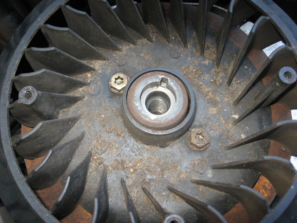 Close-up of a dirty fan assembly with black blades and a metal hub.