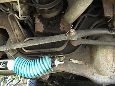 1995 Ford Bronco - Underside view of a vehicle's steering linkage with a blue bellows boot.