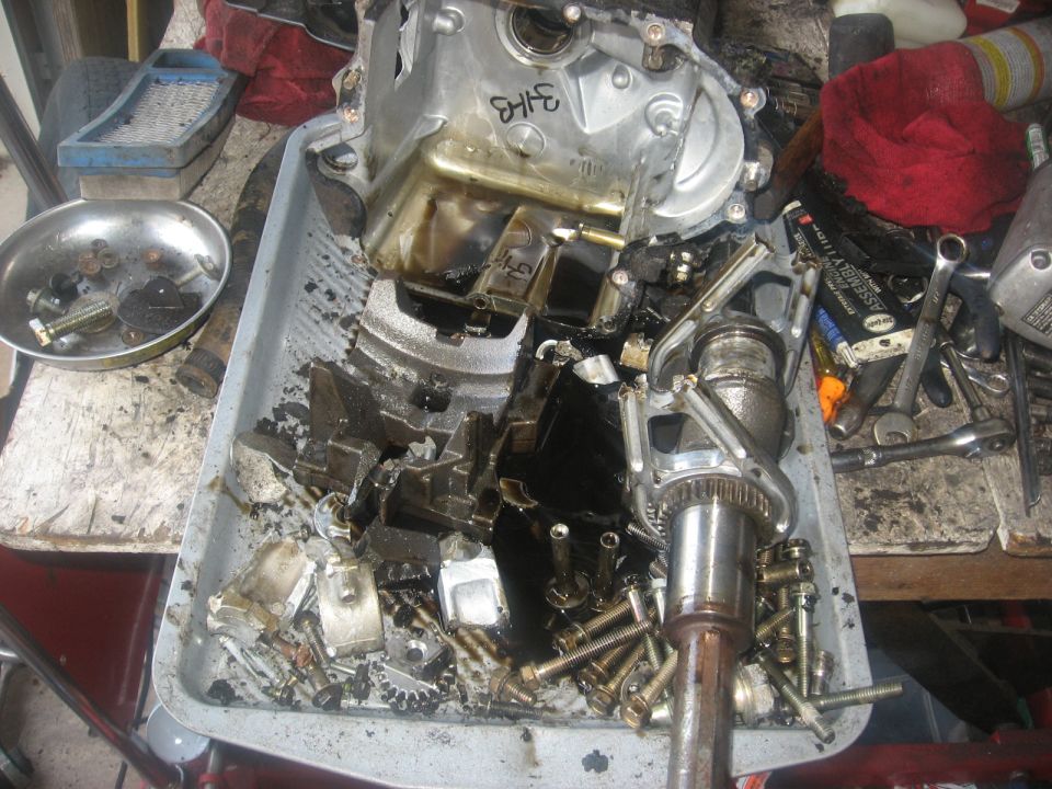 Disassembled engine or transmission parts with tools on a workbench.