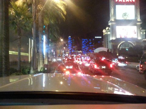 1979 Ford Bronco - A traffic jam at night on a city street lined with palm trees and illuminated buildings. The view is from the perspective of a driver looki…