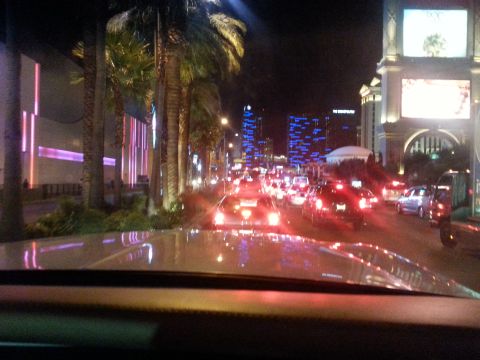 1979 Ford Bronco - Driving through a city at night with heavy traffic and bright lights from buildings and signs.