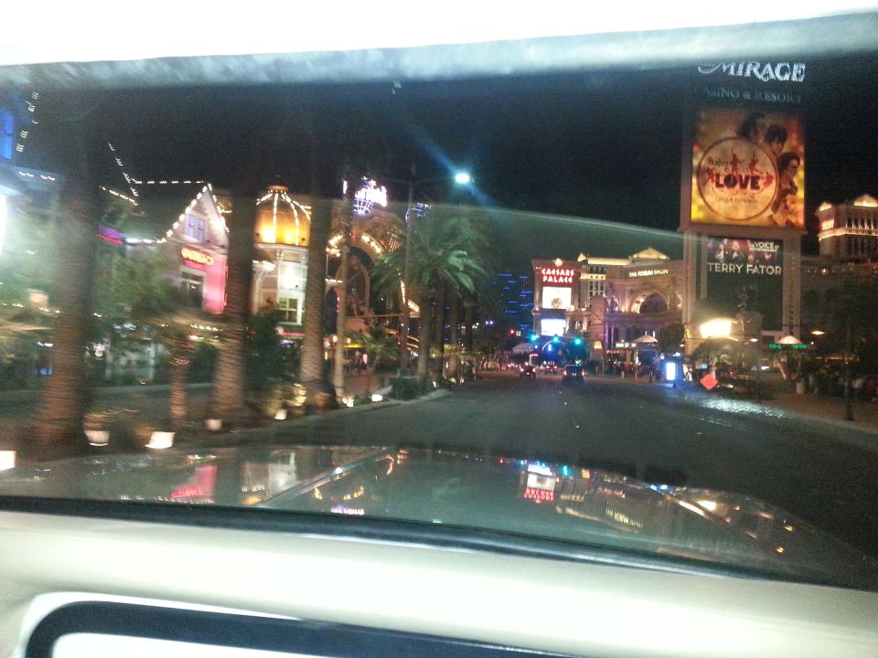 View of Las Vegas Strip at night from inside a vehicle, showing casinos and lights
