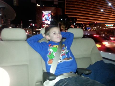 1979 Ford Bronco - Child enjoys a nighttime drive through the city, hands behind head in a car seat.