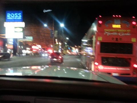 1979 Ford Bronco - Driving at night through a city street, passing a red bus with illuminated signs.