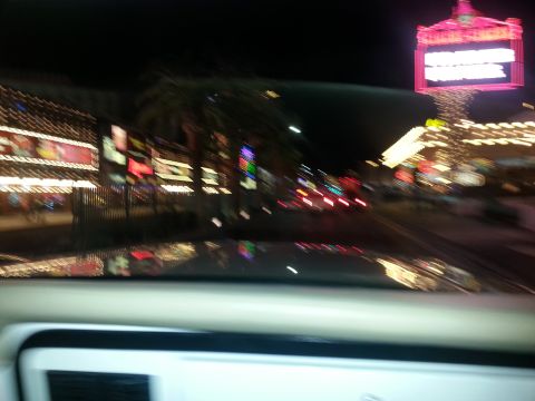 1979 Ford Bronco - Driving through a vibrant, illuminated street scene at night, with reflections on the car's surface.