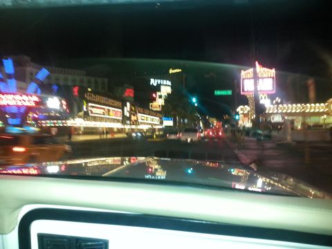 1979 Ford Bronco - View from inside a vehicle driving down a street lined with casinos and entertainment venues at night.