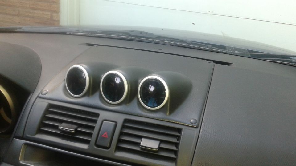 Dashboard interior with three aftermarket gauges mounted above air vents