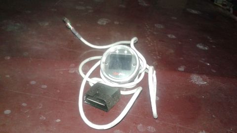 2008 Mazda 3 - A digital gauge with an OBD-II connector and white cable is shown, likely an aftermarket accessory.