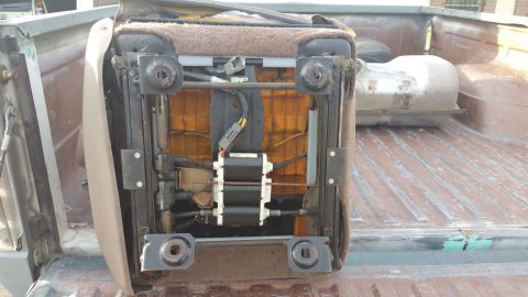1995 Ford F-150 - The underside of a power seat, revealing its internal mechanisms and wiring, is shown removed from a vehicle.