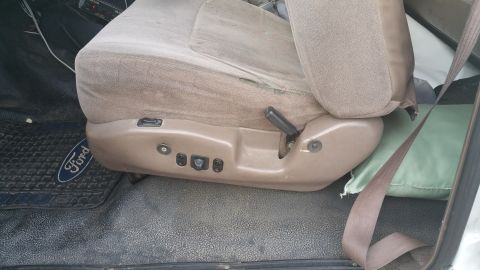 1995 Ford F-150 - Interior view of a tan cloth car seat with power controls and a Ford logo on the floor mat.