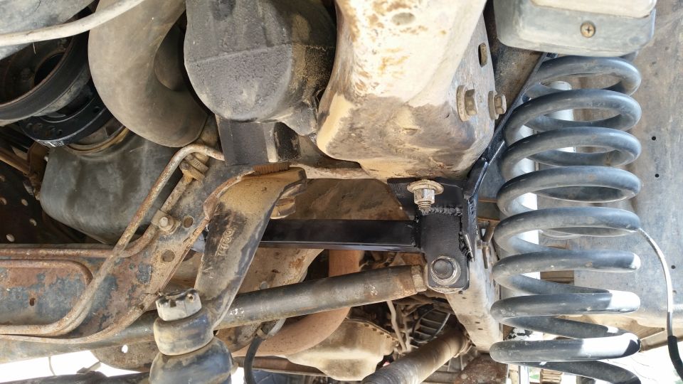 Undercarriage view of vehicle suspension with coil spring and metal bracket