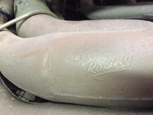 Exhaust pipe with embossed "K&N Racing" logo, showing signs of wear and dust