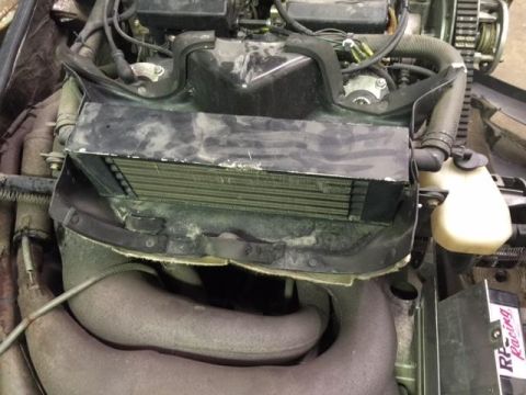 2000 Ford E350 - Close-up view of an engine compartment, showing the radiator, exhaust pipes, and various hoses. The Supermotors.net logo is visible at the…
