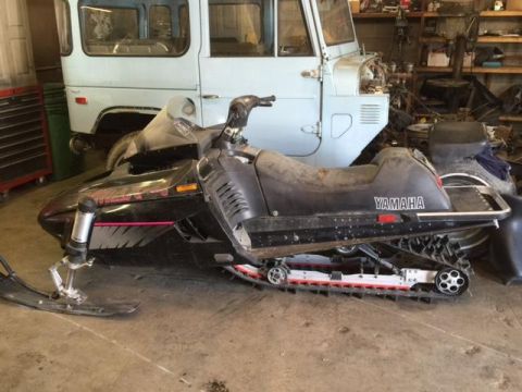 2000 Ford E350 - A Yamaha snowmobile is parked in a garage, with a light blue vehicle behind it.