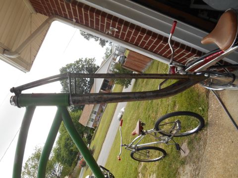 Green bicycle frame with chrome handlebars and brown seat
