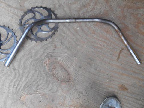 Silver bicycle handlebars and chainrings on wooden surface
