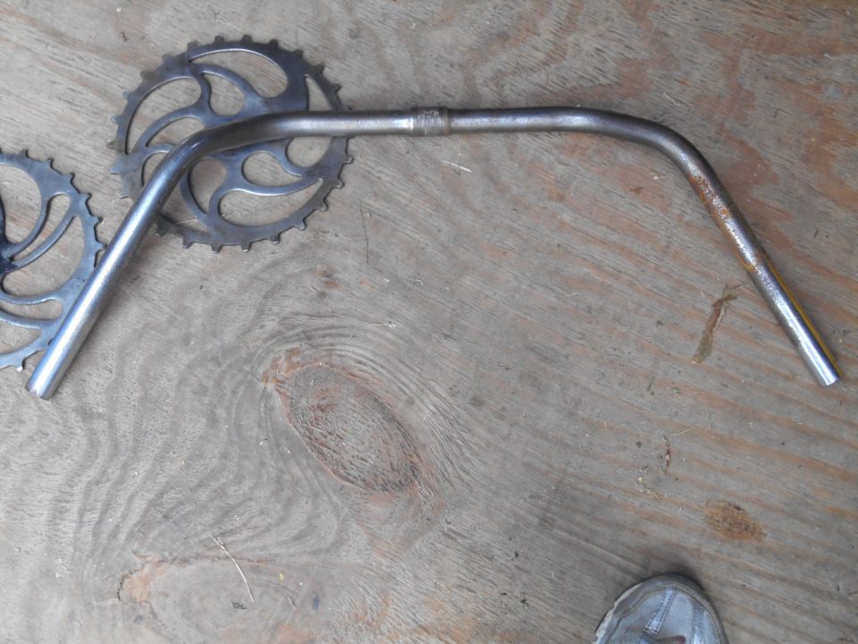 Silver bicycle handlebars and chainrings on wooden surface