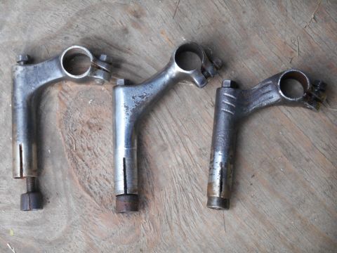 Three bicycle handlebar stems on a wooden surface