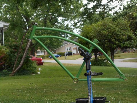 Green bicycle frame on a repair stand in a yard