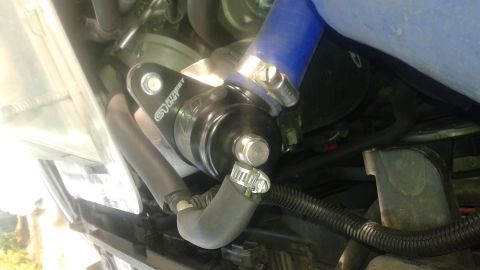 2008 Mazda 3 - Close-up of a black blow-off valve with a blue hose and metal clamps, part of a vehicle's engine.