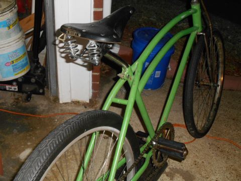 Green cruiser bicycle with black sprung seat and wide tires