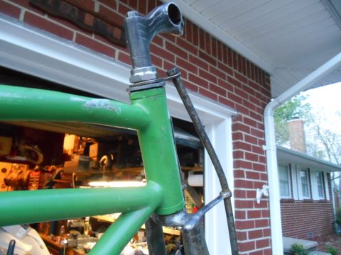 Green bicycle frame with chrome handlebars and stem, viewed from the side