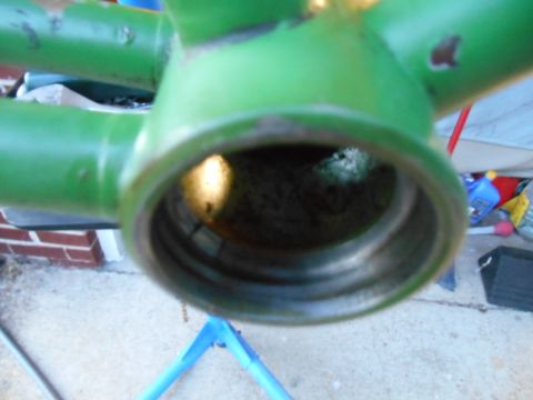 Close-up of a green painted metal frame with a hollow center, possibly part of a bicycle or machinery