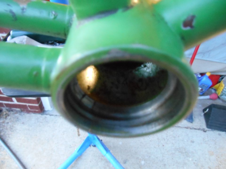 Close-up of a green painted metal frame with a hollow center, possibly part of a bicycle or machinery