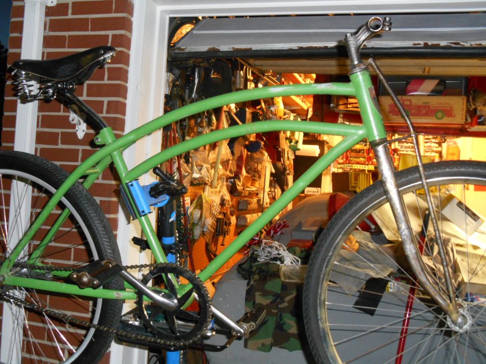 Green custom cruiser bicycle with a black sprung seat and chrome handlebars