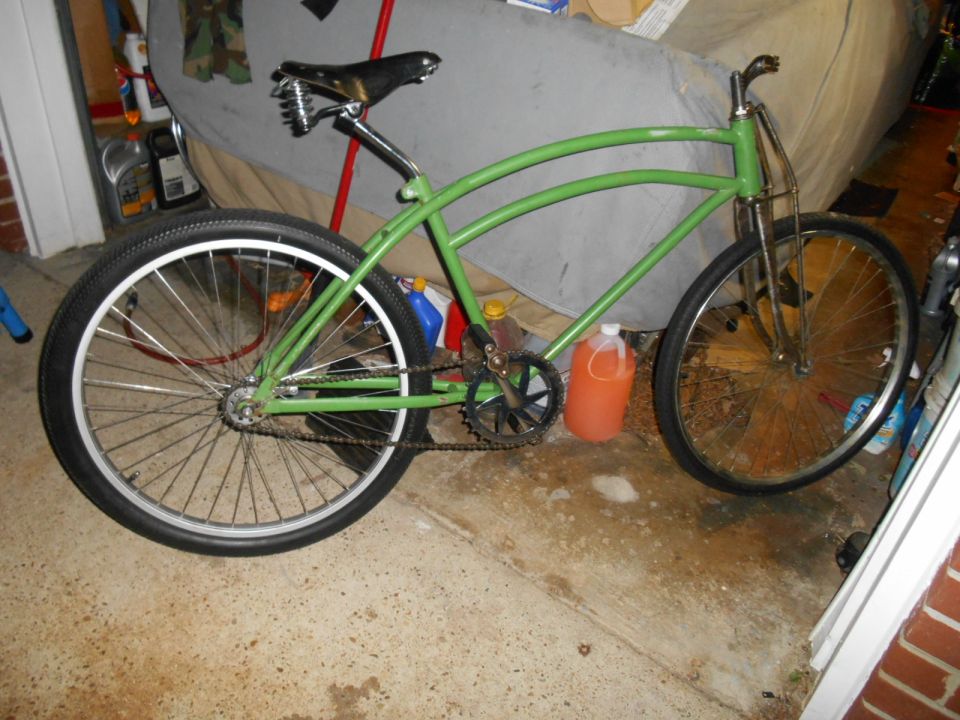 Green bicycle with a black seat and wide tires, viewed from the side
