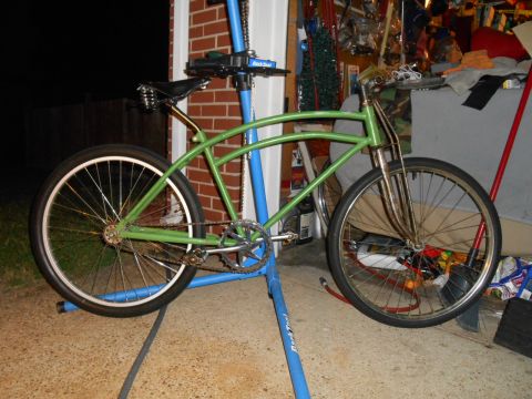 Green cruiser bicycle on a repair stand in a garage