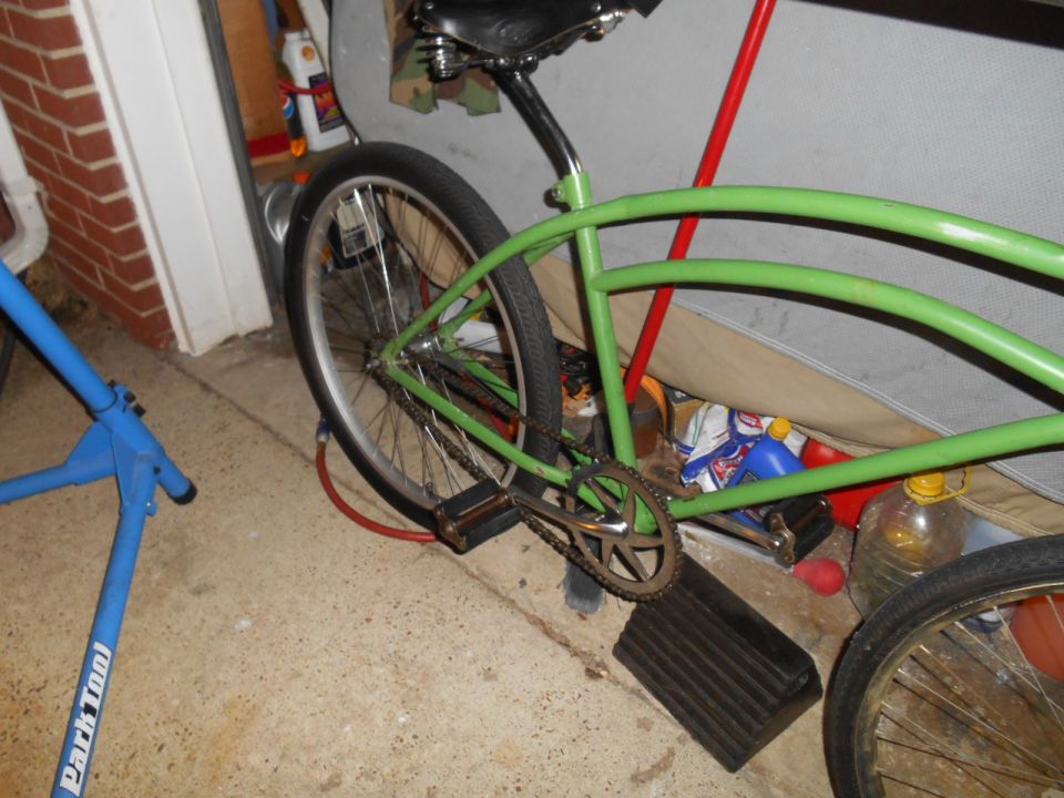 Green cruiser bicycle rear wheel and frame with black seat and pedals