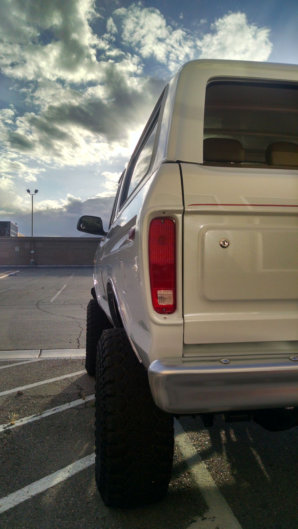Rear view of lifted white SUV with large tires, cloudy sky