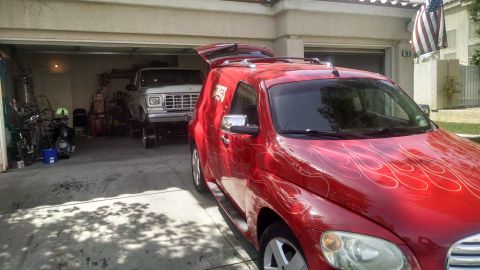 1979 Ford Bronco - A silver pickup truck is parked inside a garage, with a red car in front of it.