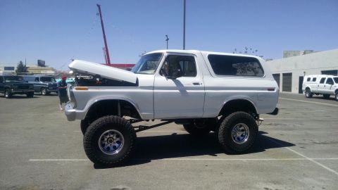 1979 Ford Bronco - White Ford Bronco with lifted suspension and open hood, parked in an outdoor lot.