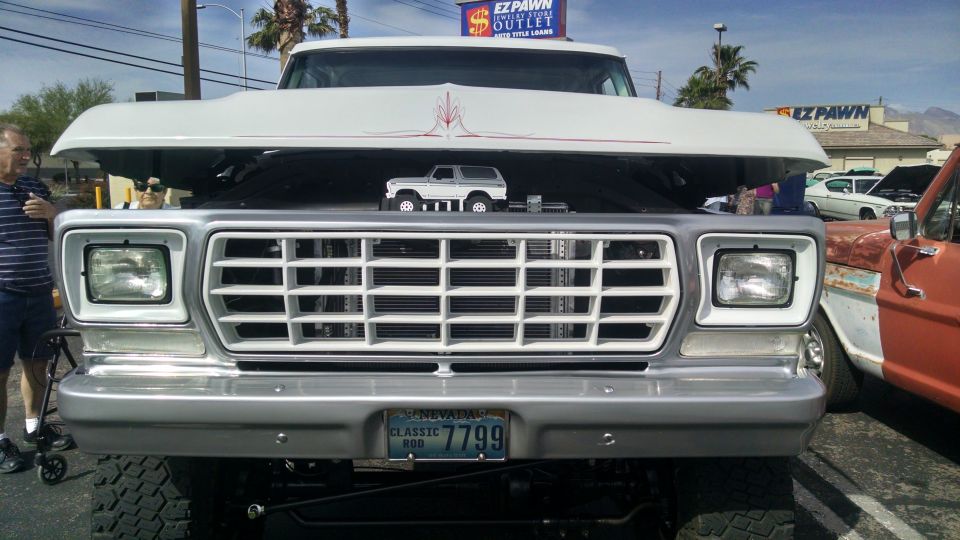 White 1977 Ford F-Series truck front grille with hood open, showing a toy Bronco