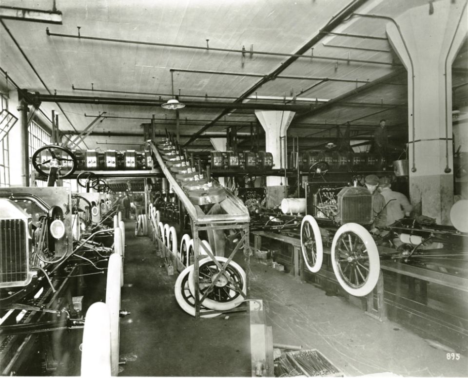 1914 Ford Model T assembly line with multiple cars on the line and workers