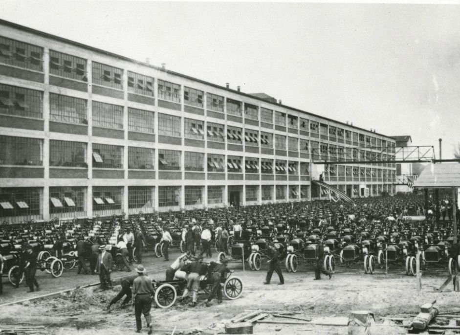 Assembly line with rows of 1914 Ford Model Ts outside a factory