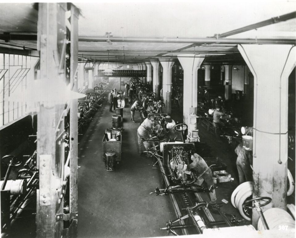Assembly line in a factory with workers building cars