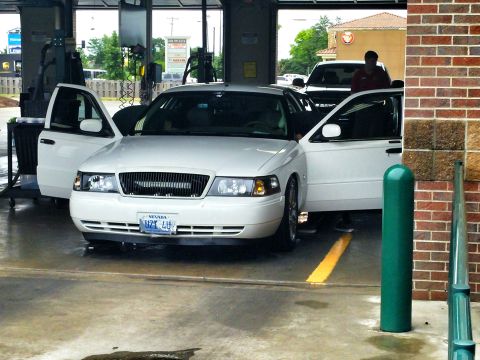 2000 Mercury Grand Marquis - A white 2000 Mercury Grand Marquis is seen with its doors open at a car wash, with another vehicle visible in the background.