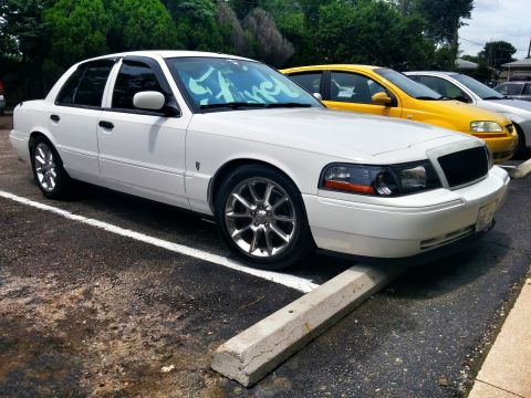 2000 Mercury Grand Marquis - White 2000 Mercury Grand Marquis parked on a concrete stop with a yellow car behind it.