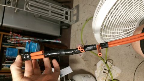 1990 Ford Bronco - Close-up view of orange vacuum lines bundled together with black tape and conduit, likely for a repair or modification.