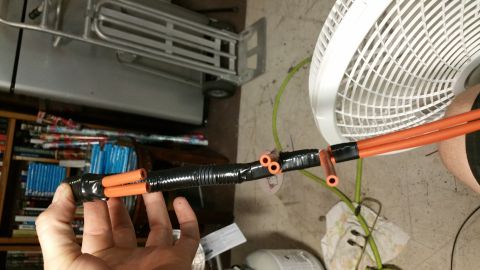 1990 Ford Bronco - Modified vacuum lines with orange tubing and black protective wrap are held in hand.