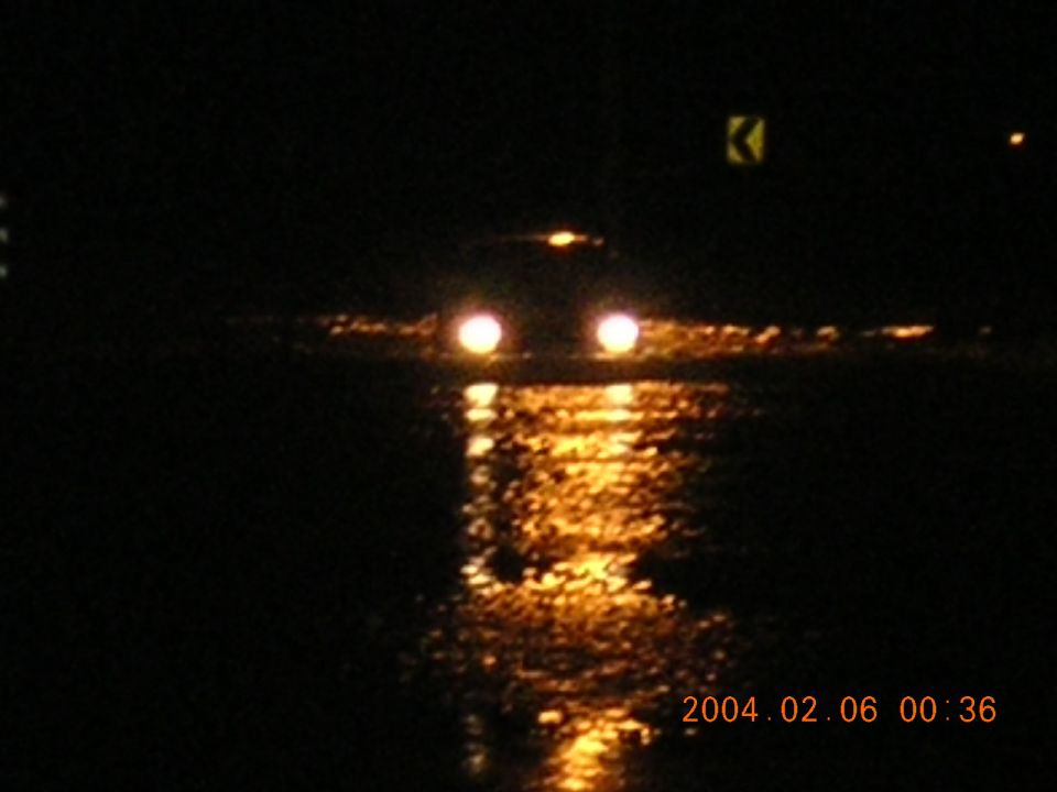 Car headlights reflected on a dark, wet road at night