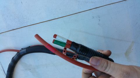 1990 Ford Bronco - Close-up of an automotive wiring harness with exposed wires being held by a hand.
