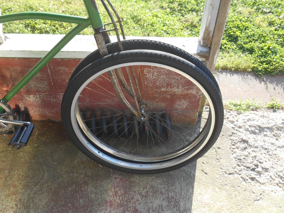 Green bicycle frame with two wheels in foreground