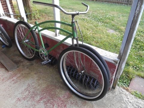 Green cruiser bicycle with chrome handlebars, parked on a porch